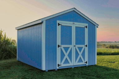 blue utility shed - blue painted wood siding with white-trimmed double doors and corners - on neat grass at either dusk or twilight