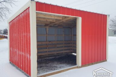 red painted loafing shed with white trim on snow-covered ground