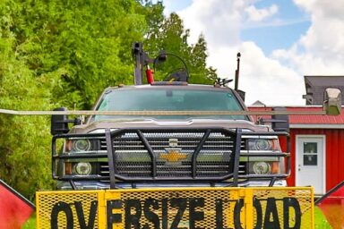 Front view of a heavy-duty truck with an “Oversize Load” banner, ready to begin our quality shed moving services in Oskaloosa IA.