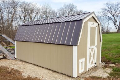 Beige shed with a brown metal roof on a gravel foundation, ready for our shed moving service