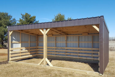Loafing shed with open access and partial wall coverage on a sunny day.