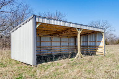 Tan loafing shed with white trim and a clean, dry entrance.